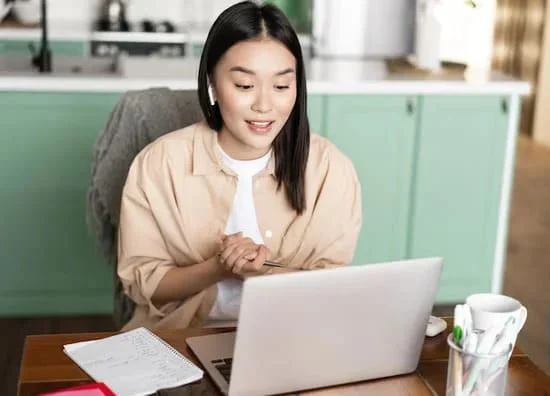 大人がパソコンでヘッドホンを着けてオンライン英会話のマンツーマンレッスンを受けている